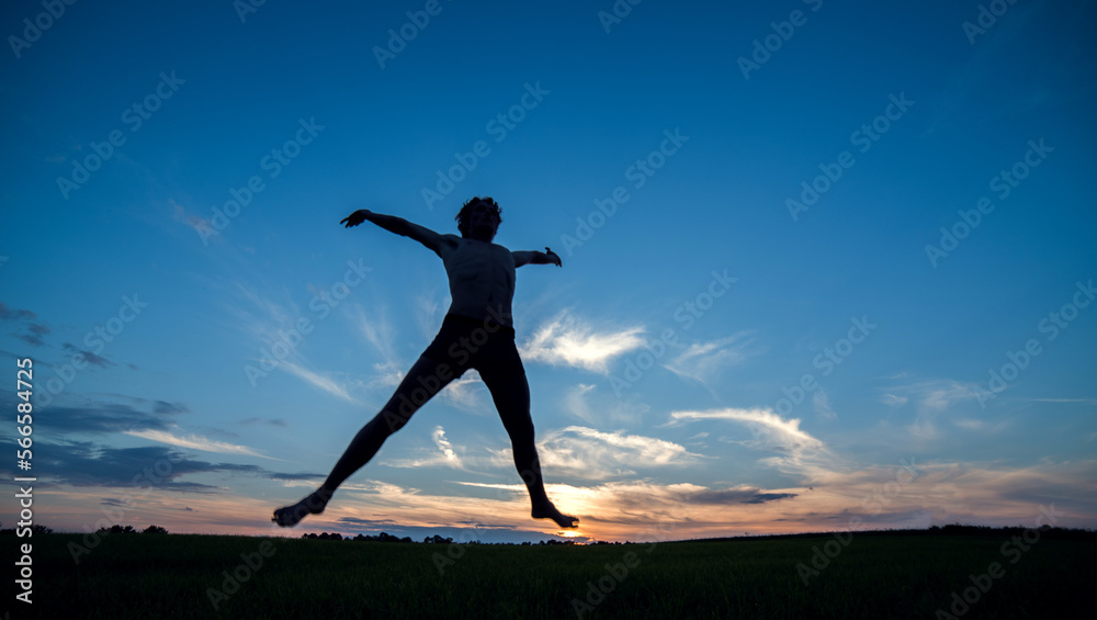 Jump of a man against the background of the evening sunset sky. Silhouette.