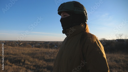 Female ukrainian army soldier walking at the field. Woman in military uniform and helmet going on meadow at sunset. Ukraine victory against Russian aggression. Invasion resistance concept.  © olehslepchenko