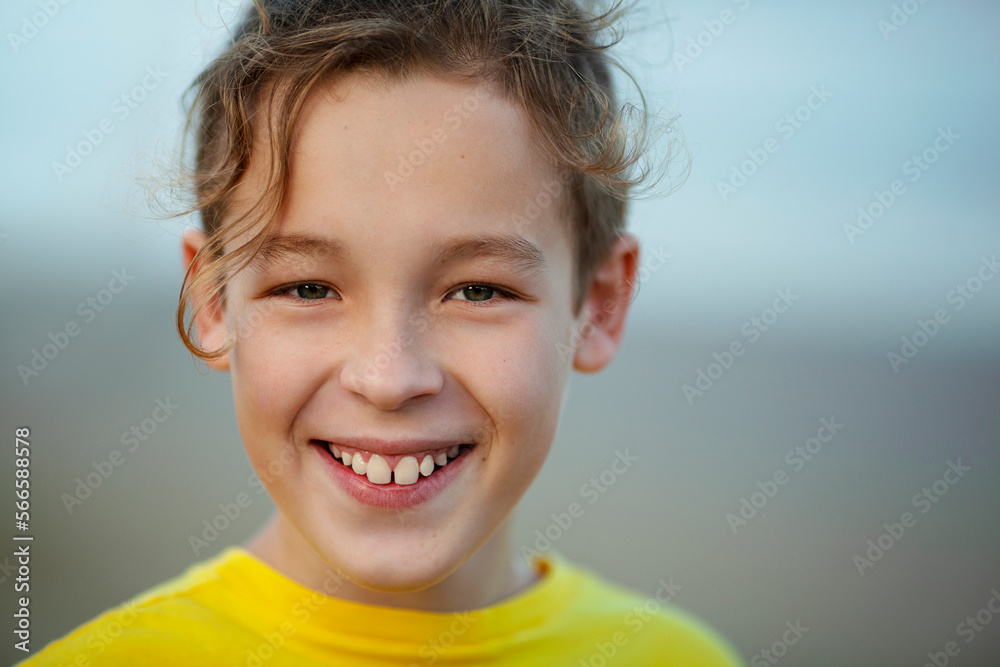 Close-up portrait of a cheerful boy with curly fair hair. Child with a big smile looking to the camera, blurry background Close-up portrait of a cheerful boy with curly fair hair. Child with a big smile looking to the camera, blurry background