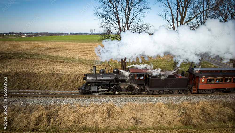 Aerial Parallel View of a Restored Antique Steam Passenger Train Traveling Thru The Countryside on a Sunny Autumn Day