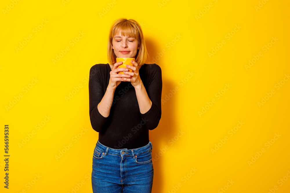 Woman holding cup of coffee on yellow color background Woman holding cup of coffee on yellow color background