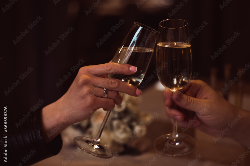 Two glasses with sparkling champagne wine in hands, concept for holiday, bokeh, in a restaurant. Romantic dinner. Man and woman are holding glasses of champagne. Concept for Valentine's day or date. Two glasses with sparkling champagne wine in hands, concept for holiday, bokeh, in a restaurant. Romantic dinner. Man and woman are holding glasses of champagne. Concept for Valentine's day or date.