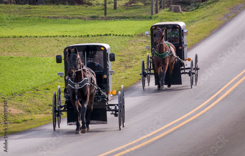 Φωτογραφία A View of Two Amish Horse and Buggies Traveling Down a Countryside Road Thru Far