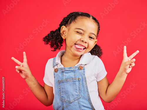 Happy, peace sign and wink with portrait of girl for summer, happiness and funny face. Meme, fashion and smile with child and hand gesture for youth, comedy and positive in red background studio photo