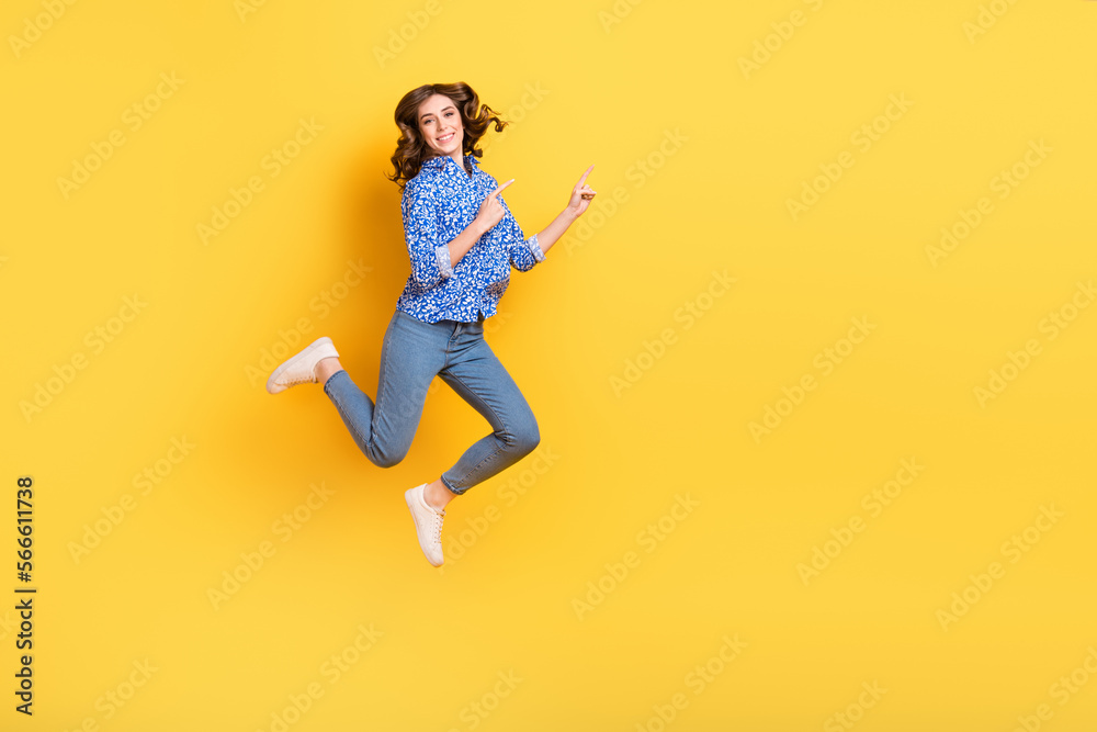 Full body portrait of excited crazy lady jumping indicate fingers empty space isolated on yellow color background