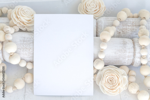 Blank, white paper card invitation with wooden beads and flowers farmhouse styled mock-up