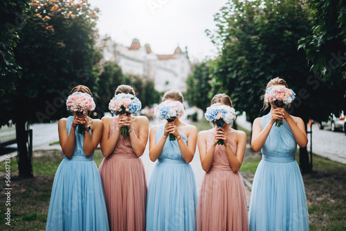 Bridesmaids at wedding with bouquets in hands. Girl in colored dresses for wedding.