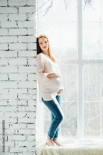 red-haired pregnant girl in a light blouse and blue jeans