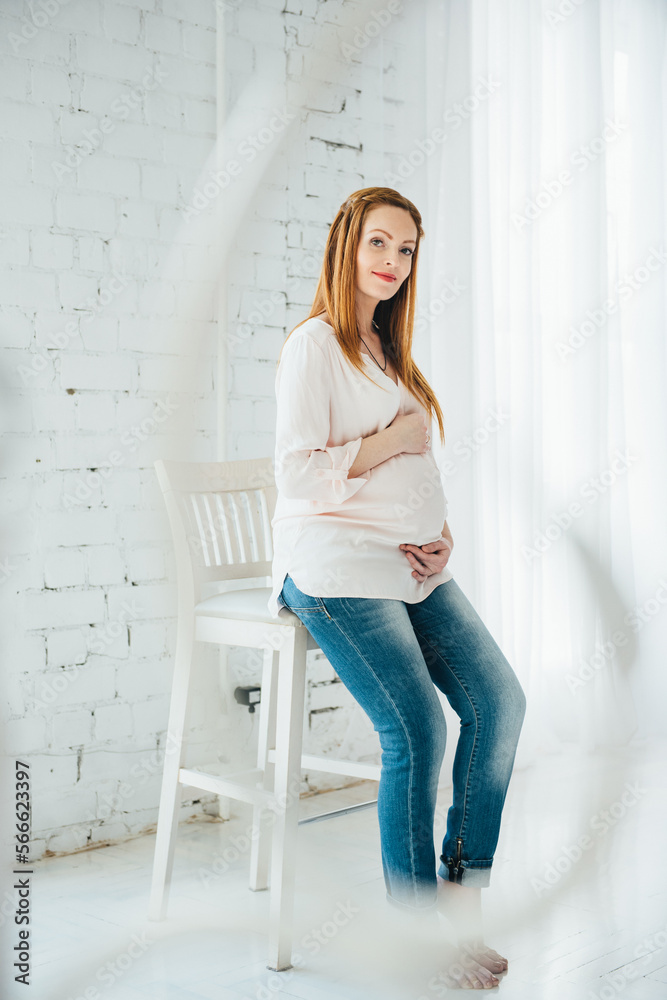 a red-haired pregnant girl in a light blouse and blue jeans a red-haired pregnant girl in a light blouse and blue jeans