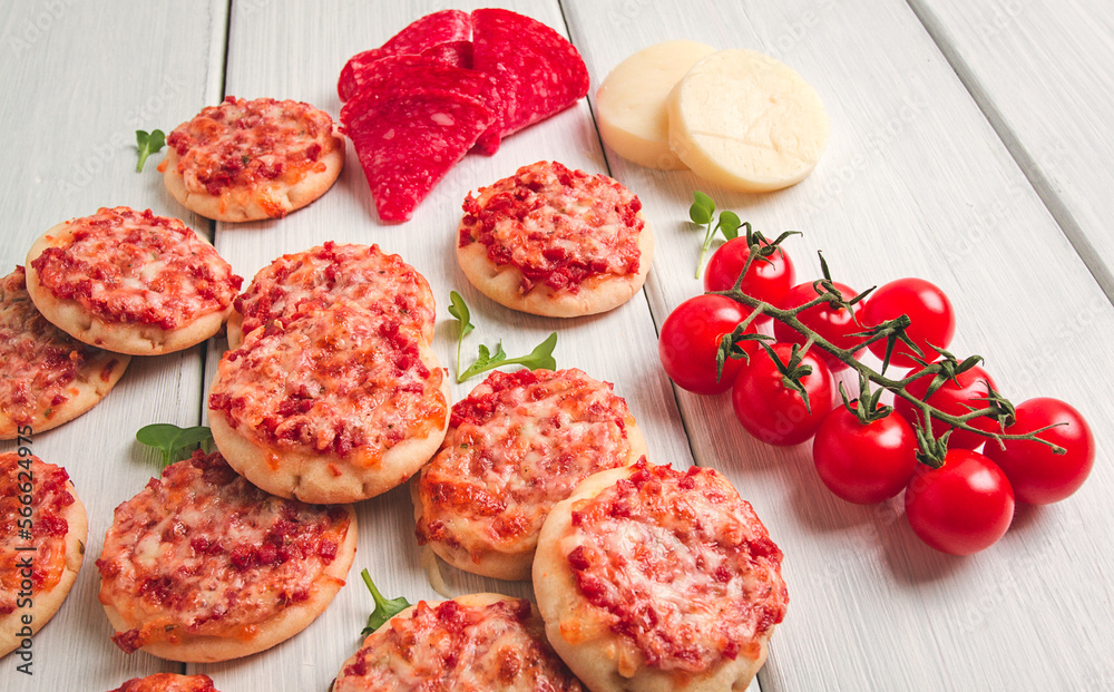 Mini pizzas, salami with mozzarella cheese, on a white table, top view, no people, Mini pizzas, salami with mozzarella cheese, on a white table, top view, no people,