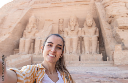 Horizontal selfie viewof young beautiful smiling tourist woman with Abu simbel temple in the background