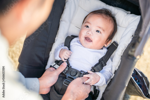 おでかけ先でベビーカーに乗ってパパにシートベルトをつけてもらう赤ちゃん photo