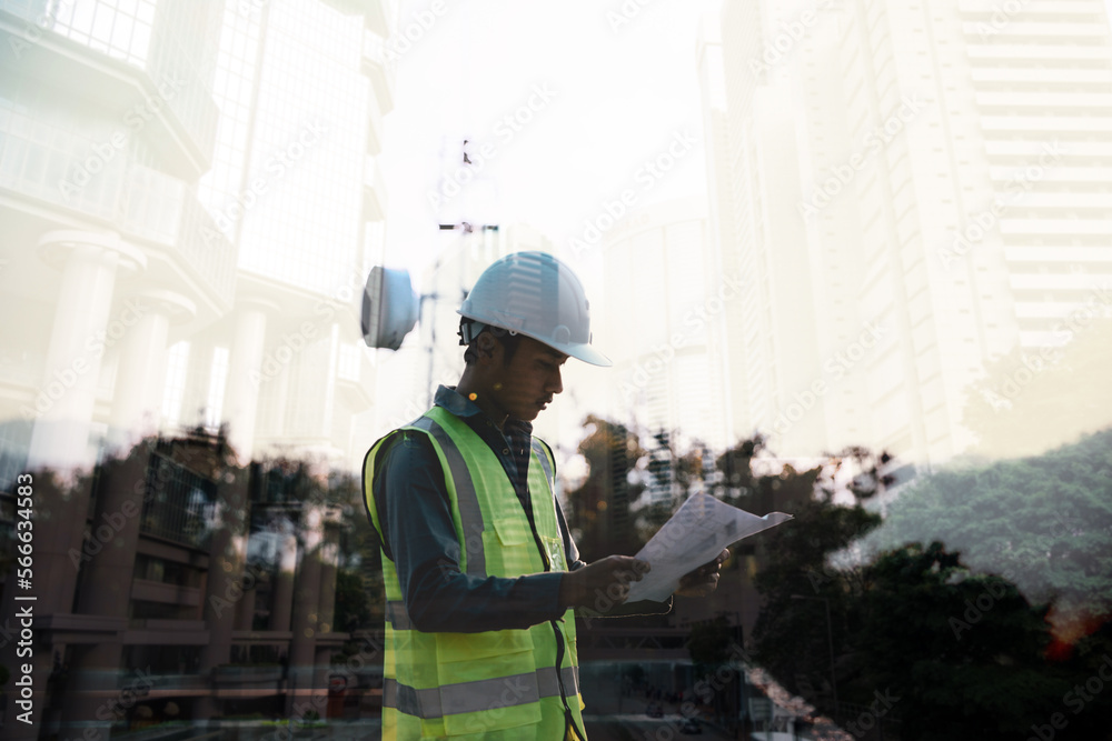 Double exposure image of engineer civil and construction worker with safety helmet and construction drawing against the background of surreal construction site in the night city or dark cityscape.