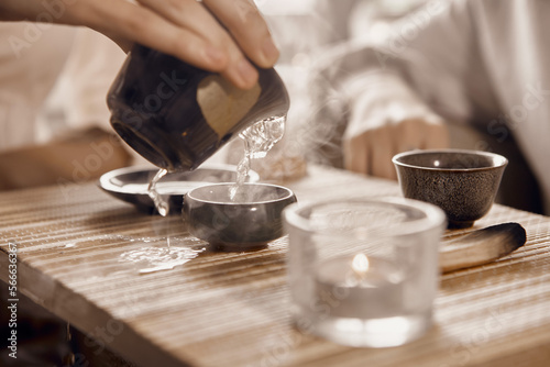 A close-up shot of a Chinese tea ceremony. On the table there is a gaiwan, bowls, a tea keeper and a palo santo