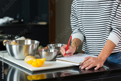 Woman checking recipe while cooking apple pie