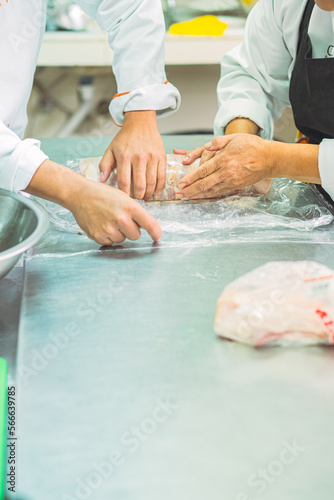 Crop cooks rolling meat in clingfilm photo