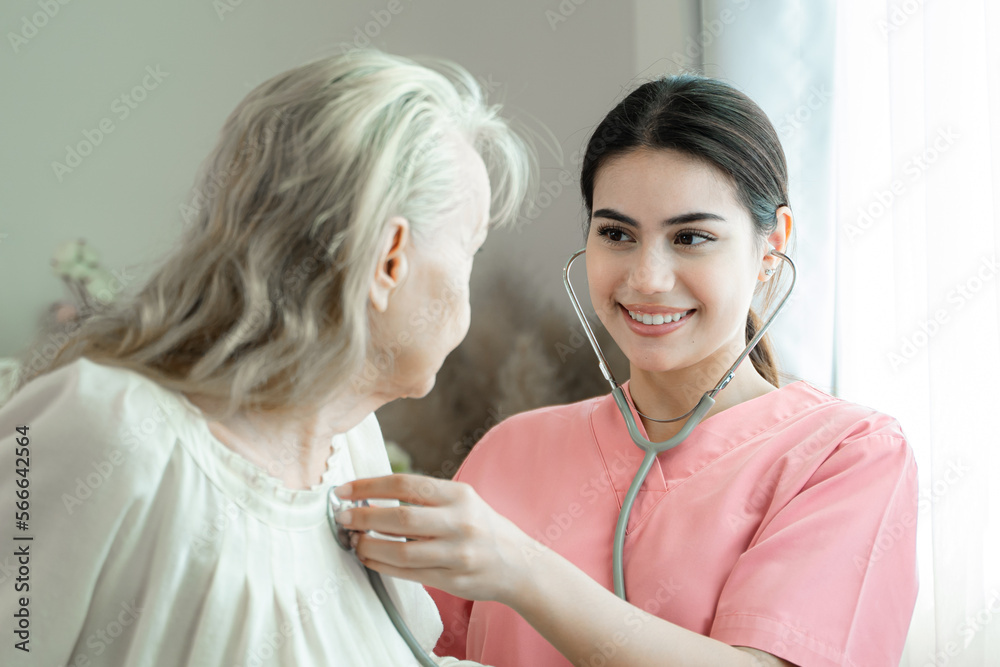 Female caregiver listening to the heart and breathing of an older woman through a stethoscope on his chest,Medical care for the elderly at home concept.