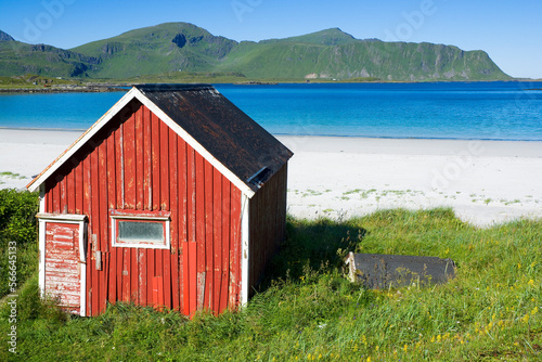 Traditional red wooden hut by Ramberg beach, Lofoten, Norway photo