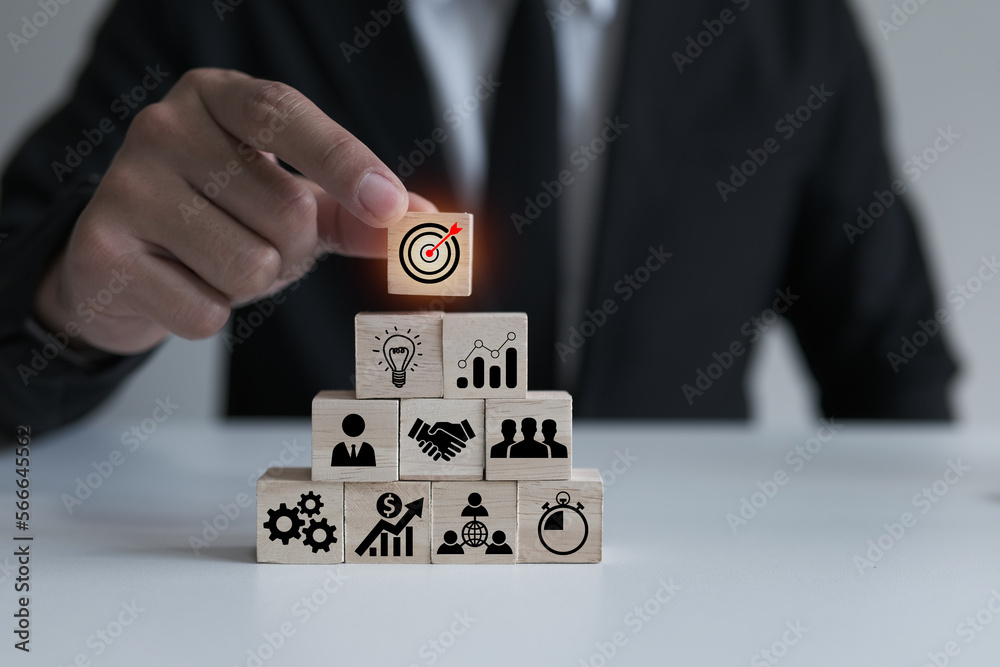 Businessmen pick up wooden cubes with target focus icons, success focus concept by goal setting and strategizing and business cooperation, good tools and communication enable business growth. Businessmen pick up wooden cubes with target focus icons, success focus concept by goal setting and strategizing and business cooperation, good tools and communication enable business growth.