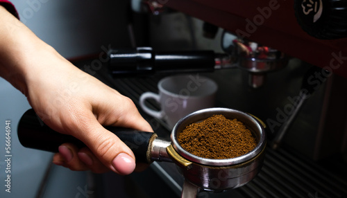 The barista's hand holds a holder with ground fresh coffee. Making coffee in a coffee machine in cafe. Close-up. Selective focus.