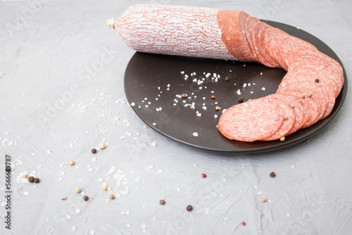 Thin sliced salami on a ceramic black plate photo