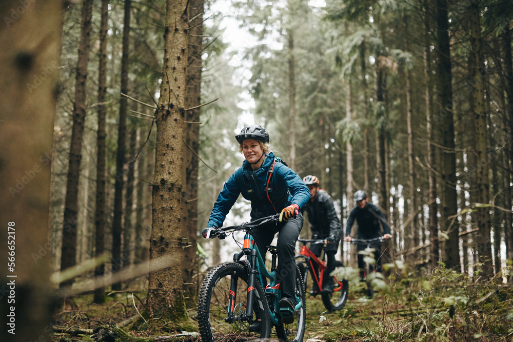 Smiling woman mountain biking in a forest with friends Smiling woman mountain biking in a forest with friends