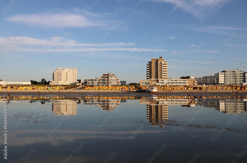 Skyline von Cuxhaven spiegelt sich in der Nordsee bei beginnender Ebbe im Sommer am Abend 