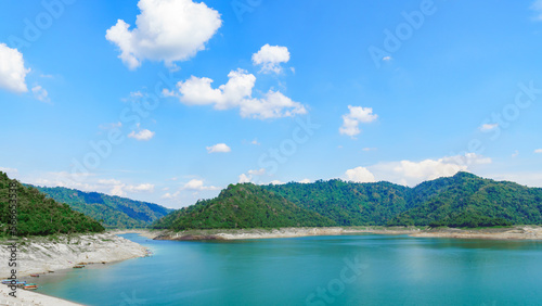 Dam view with emerald green water  There are green mountains  and bright sky © Eakkarach