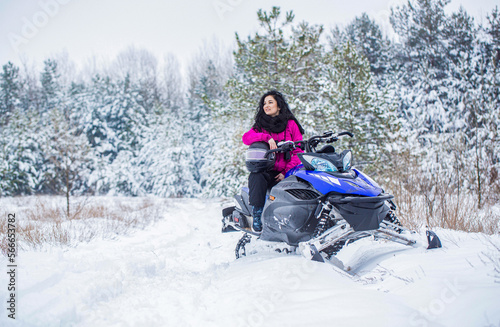 Woman is riding snowmobile in mountains. Girl on a sports snowmobile in a mountain forest. Athlete rides a snowmobile in the mountains. Snowmobile in snow. Concept winter sports