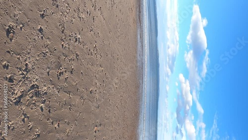 Vertical video of the ocean and sand at Nairn Beach in Scotland. Sunny day. Beautiful scenic Scottish ocean scene.  Beach resort near Inverness. 4K walking video.