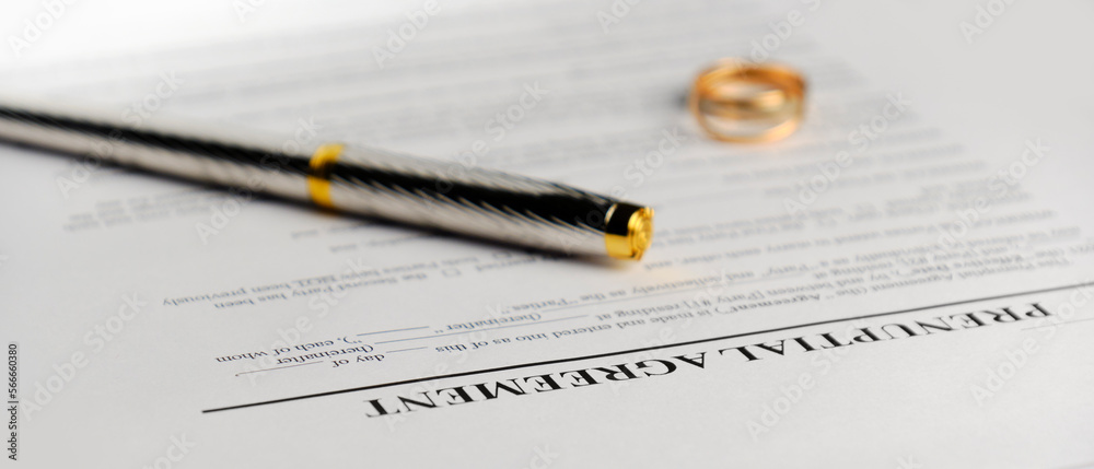 A marriage prenuptial agreement, focus on the title of the document, fountain pen and wedding ring blurred in the background A marriage prenuptial agreement, focus on the title of the document, fountain pen and wedding ring blurred in the background