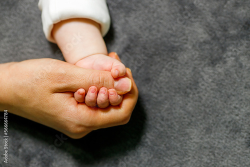 Close up mother holding tiny hand of little newborn baby boy girl, helping hands, bonding different generations. Happy motherhood concept.