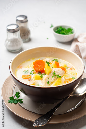 Creamy fish chowder soup in bowl on concrete background