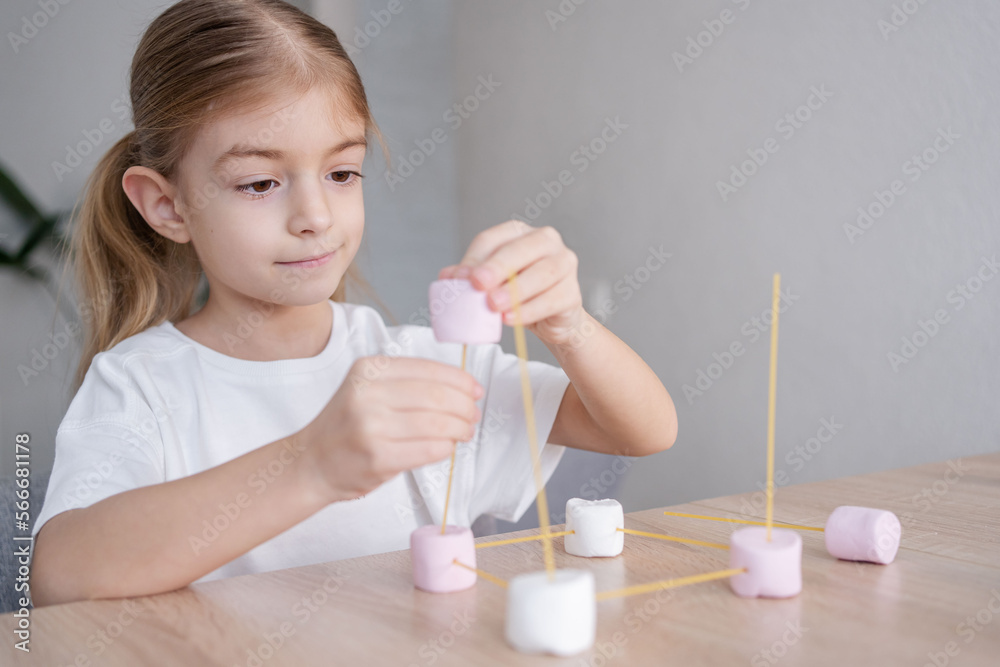 child girl playing and creating molecular shapes model from marshmallow and spaghetti. School kid using molecular handmade model for studying physics. child girl playing and creating molecular shapes model from marshmallow and spaghetti. School kid using molecular handmade model for studying physics.