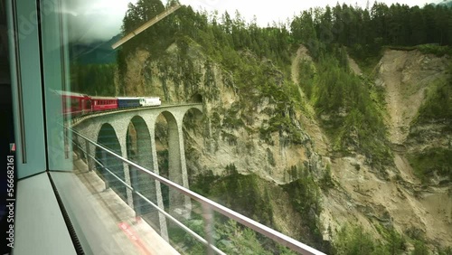 Inside famous Glacier Express red swiss train on Landwasser viaduct bridge in Swiss Alps. Rhaetian Railway famous route Zermatt to St. Moritz. Switzerland summer tourism.