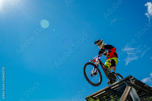 rider drops downhill in background blue sky