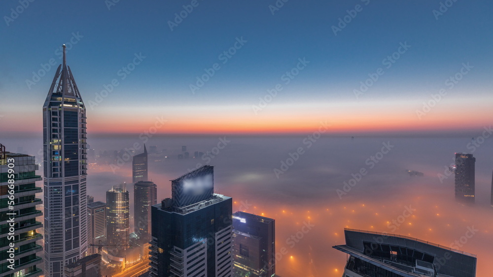 Rare early morning winter fog above the Dubai Marina skyline and skyscrapers lighted by street lights aerial night to day .