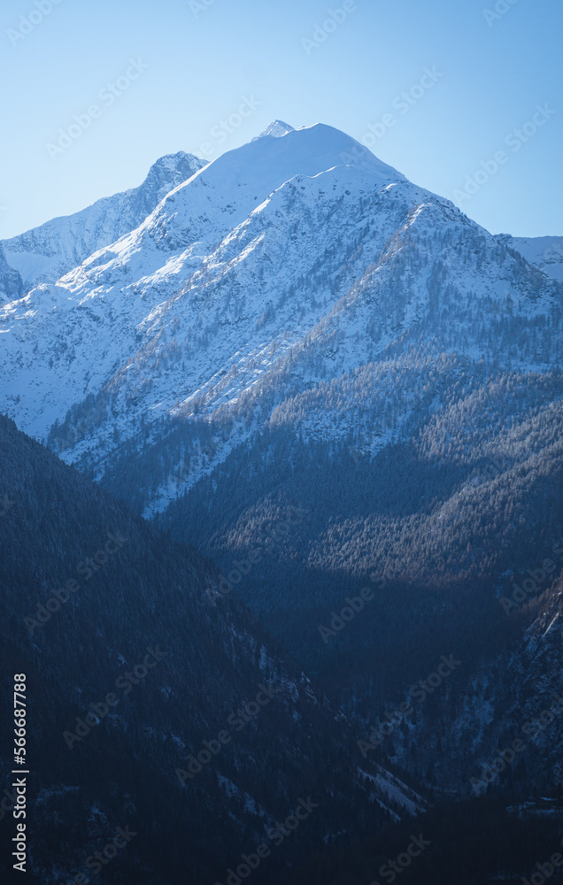 The Valtellina mountains, with its pastures, woods and fresh snow, during a wonderful winter day near the village of Sondrio, Italy - January 2023.