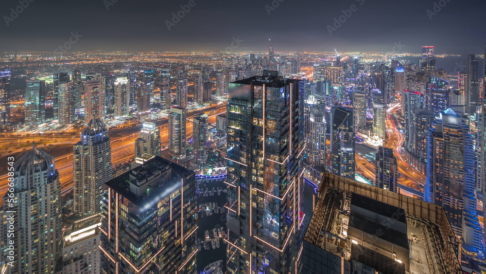 Dubai Marina and JLT district with traffic on highway between skyscrapers aerial night .