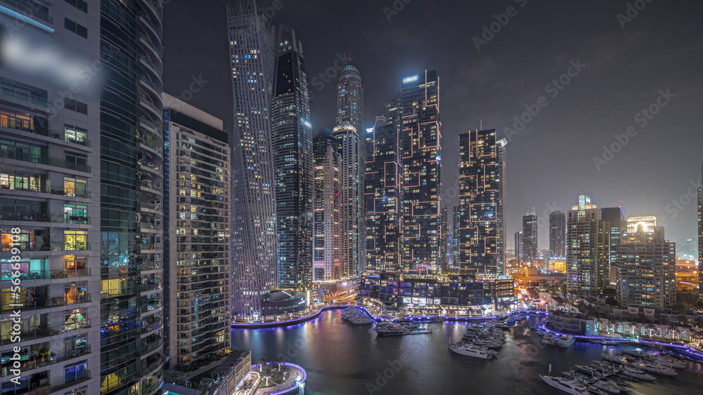 Panorama showing Dubai marina tallest skyscrapers and yachts in harbor aerial night . Panorama showing Dubai marina tallest skyscrapers and yachts in harbor aerial night .