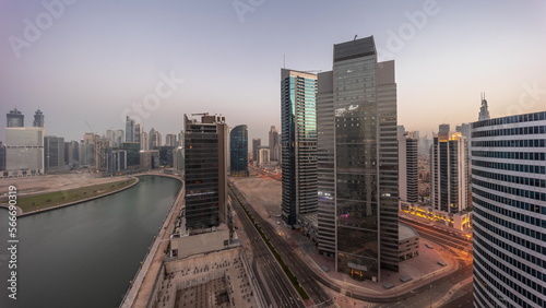 Cityscape of skyscrapers in Dubai Business Bay with water canal aerial night to day