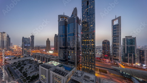 Aerial view of Dubai International Financial District with many skyscrapers day to night .