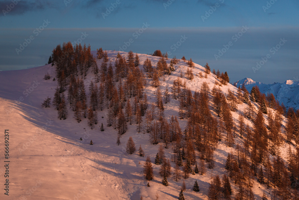 Sunset over the Italian alps of Valtellina, near the village of Sondrio, Italy, with fresh snow and a spectacular view of the woods and peaks - January 2023