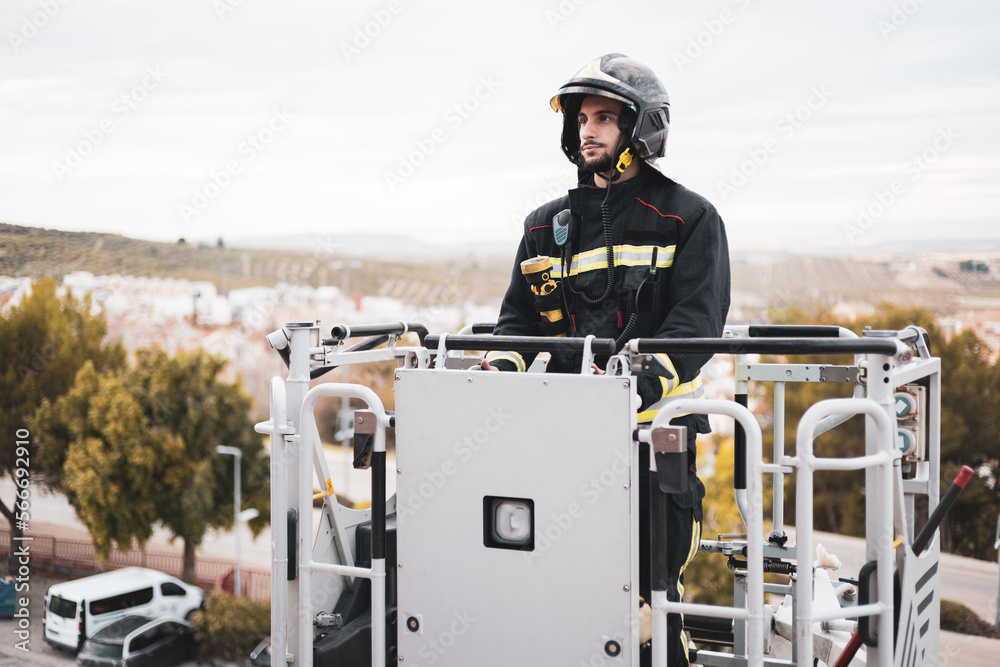 A Spanish firefighter is driving the controls of a basket of a crane truck to reach a building.