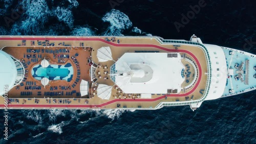 Aerial top view of big cruiser ship in sea. Track shot over the main deck with entertainment zones on it - swimpool, cinema. mini golf. People have fun