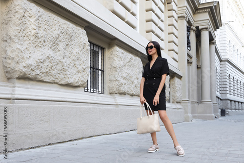 Young woman with stylish bag on city street. Space for text