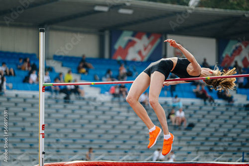 female athlete high jump on background fan stands