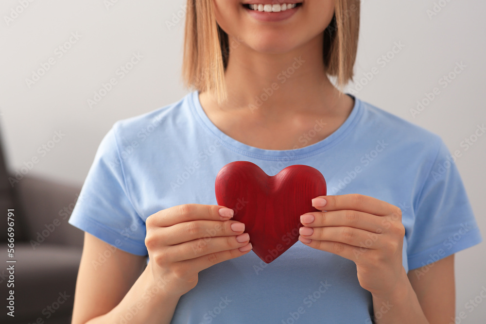 Young woman holding red heart indoors, closeup. Volunteer concept Young woman holding red heart indoors, closeup. Volunteer concept