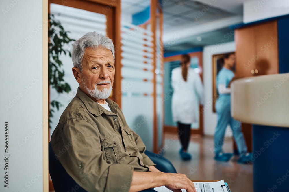 Portrait of senior man in waiting room at doctor's office looking at camera.