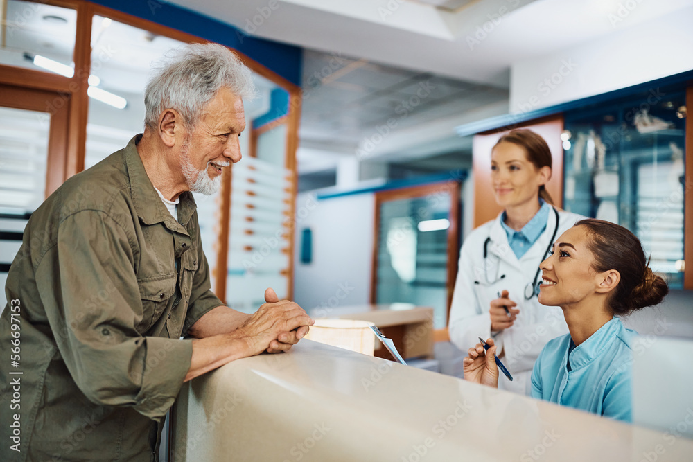 Happy senior man talks to nurse while checking in at doctor's office. Happy senior man talks to nurse while checking in at doctor's office.